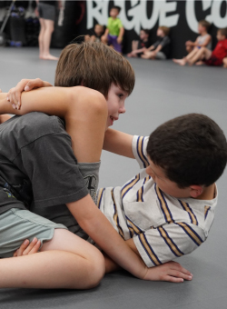 two children practicing jiu jitsu with one child in the triangle position