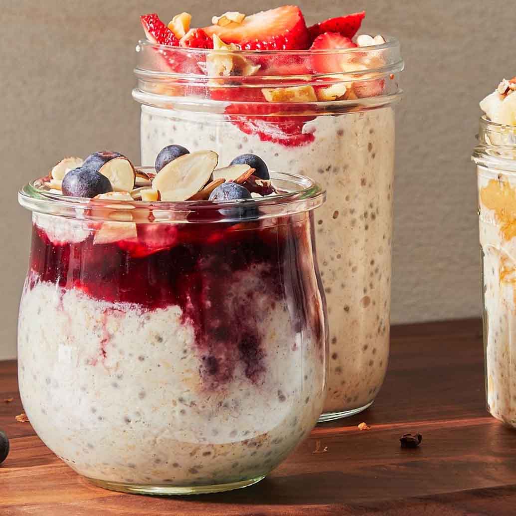 basil seed filled over night oats in a glass jar topped with various berries and nuts