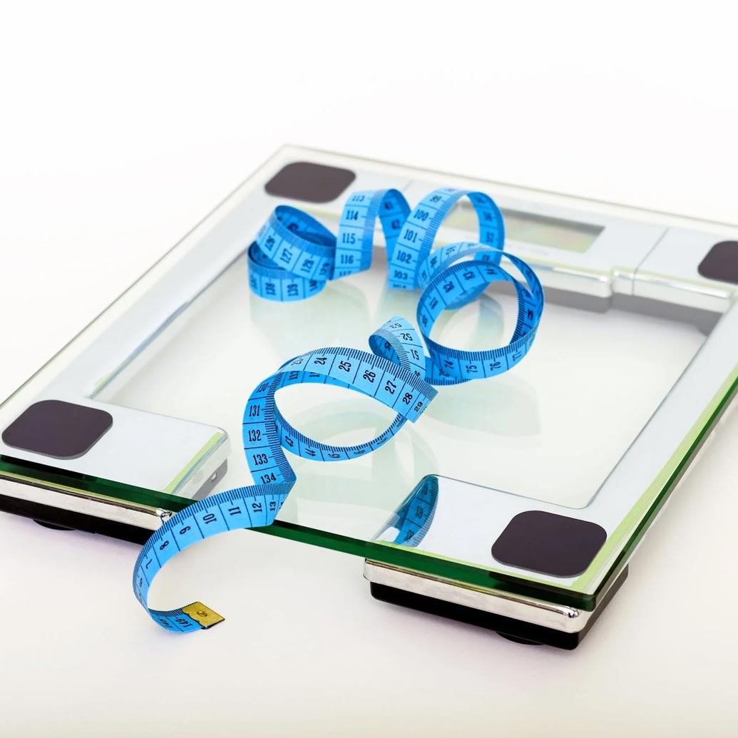 Blue flexible measuring tape sitting on a bathroom scale